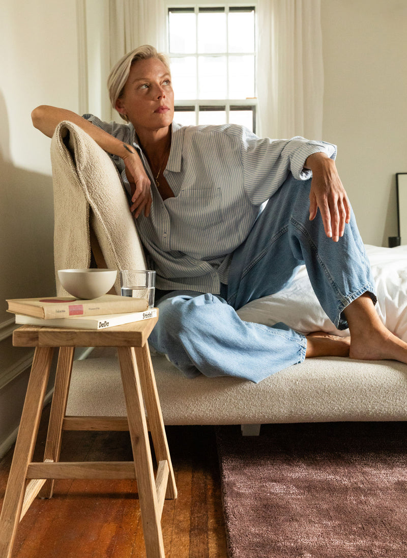 A woman sits on a Floyd Bed – Original, Upholstered